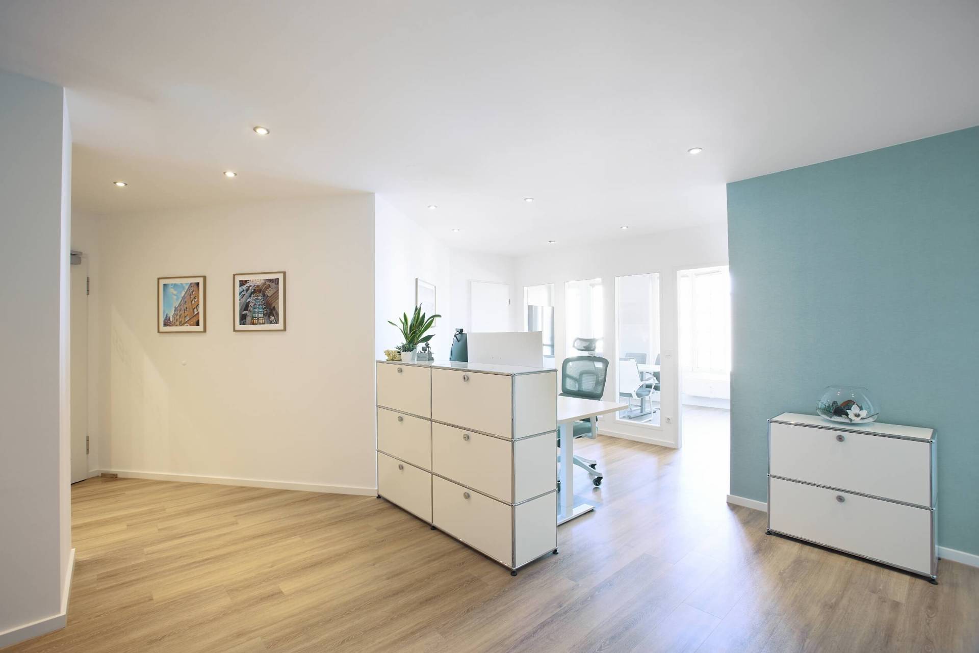 Foto: Heller Empfangsbereich mit Holzfußboden, weißem Sideboard, Pflanzen auf der Ablage und modernen Bürostühlen vor einer Glaswand